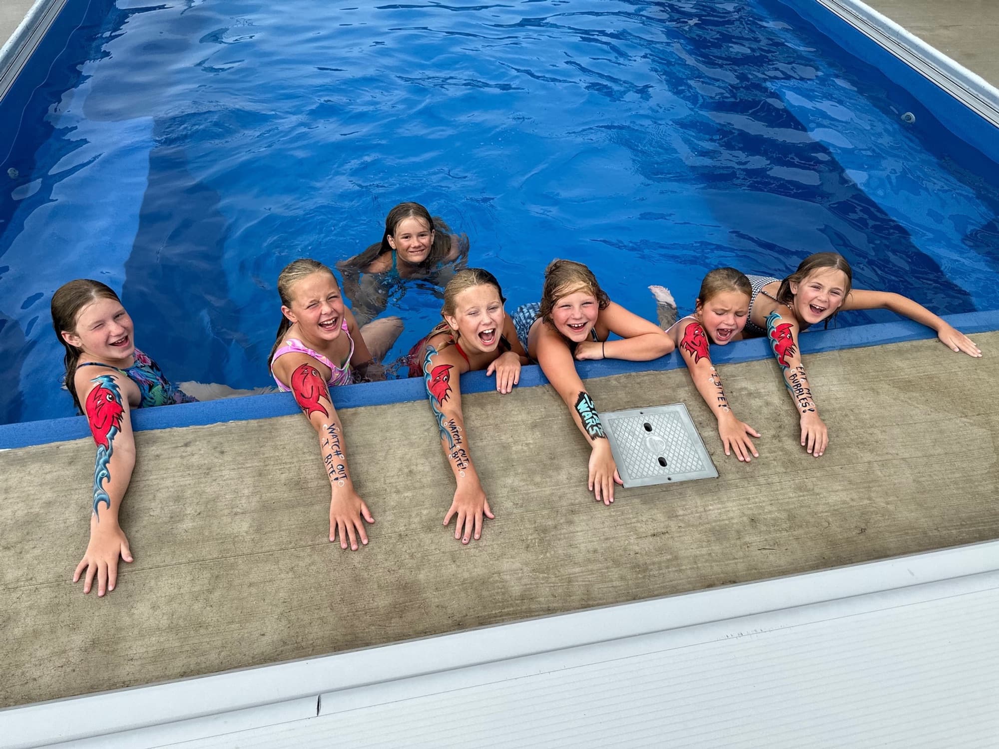 Swimmers with arm designs at the pool edge