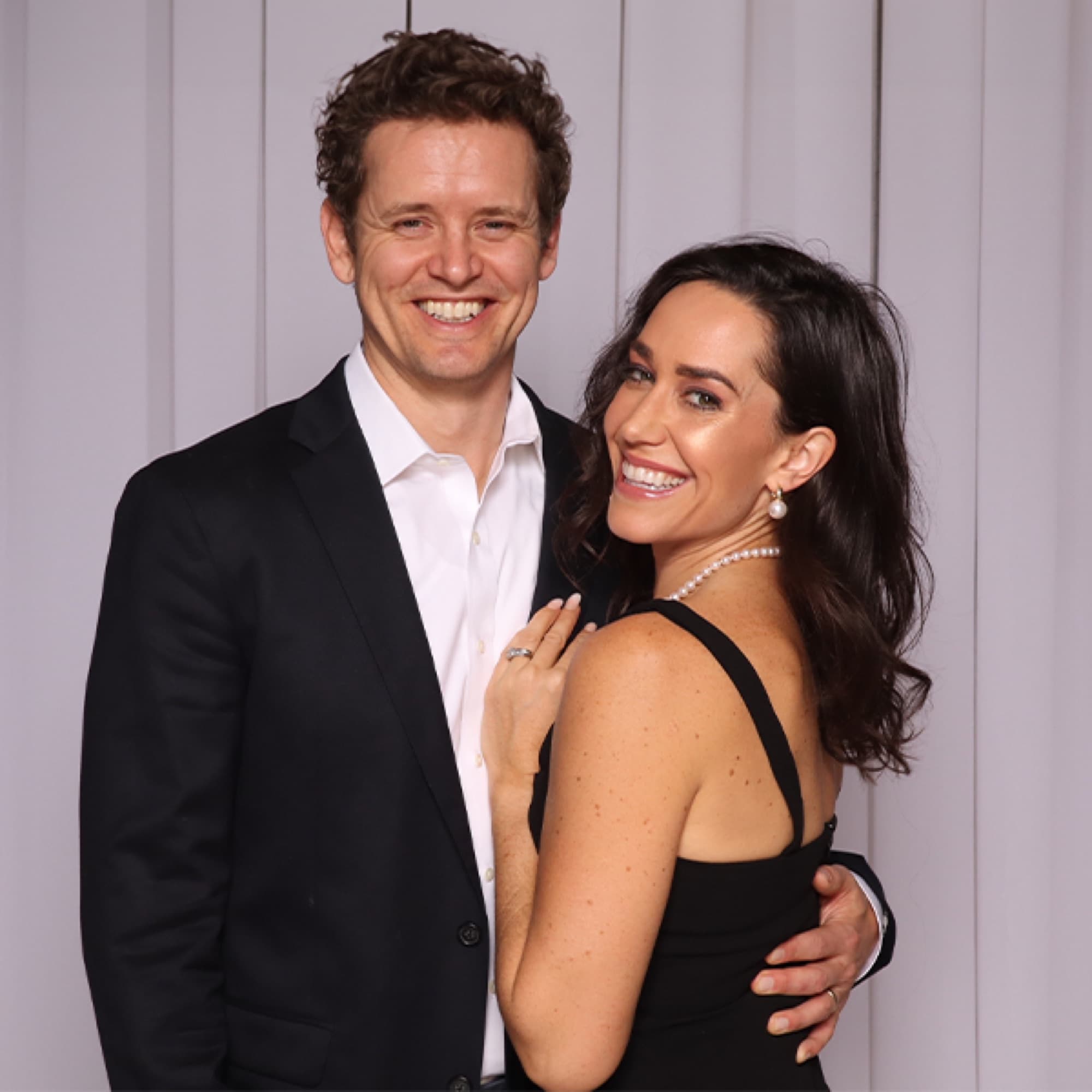 Couple laughing in front of a backdrop